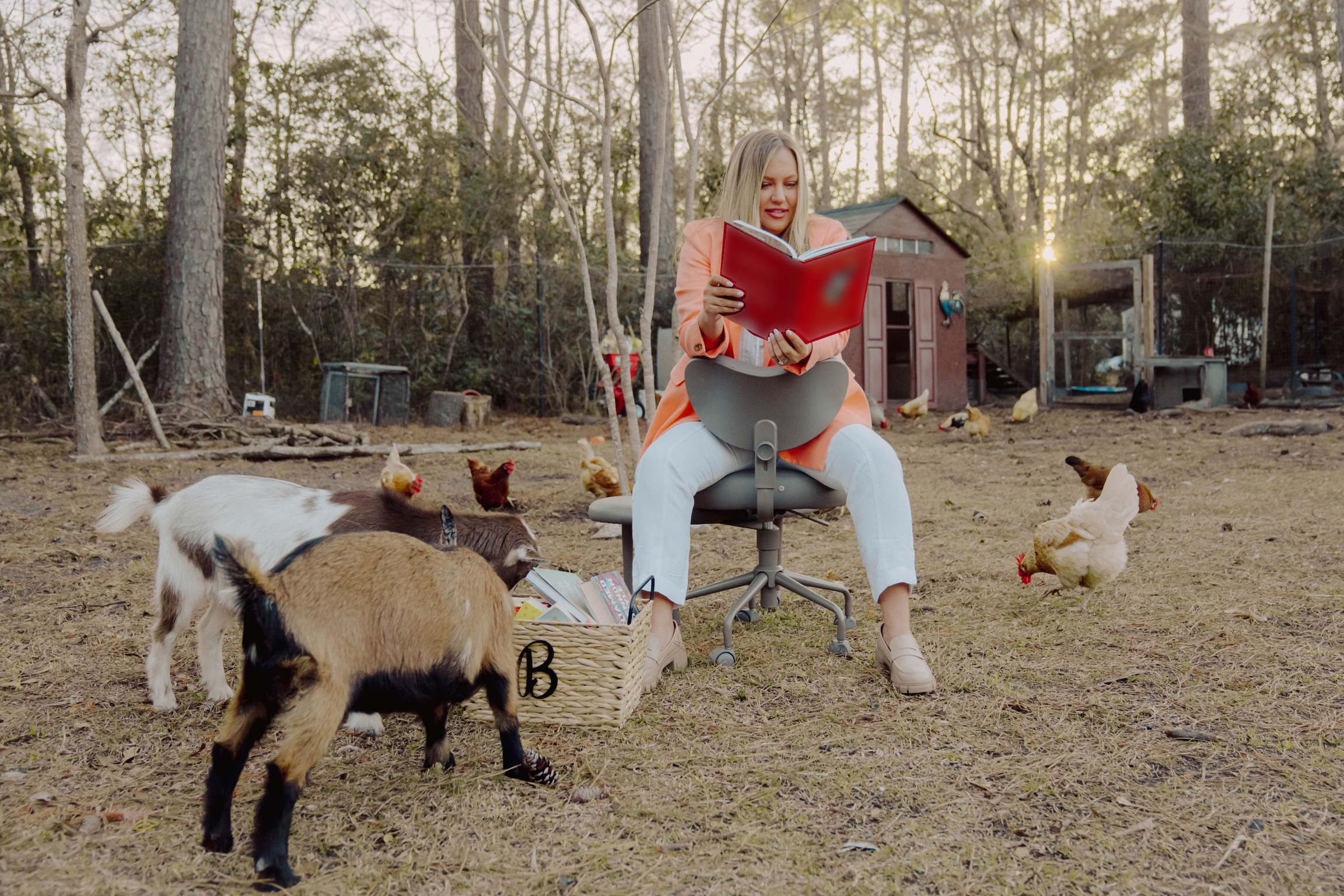 Jen reading on the farm, surrounded by goats and chickens