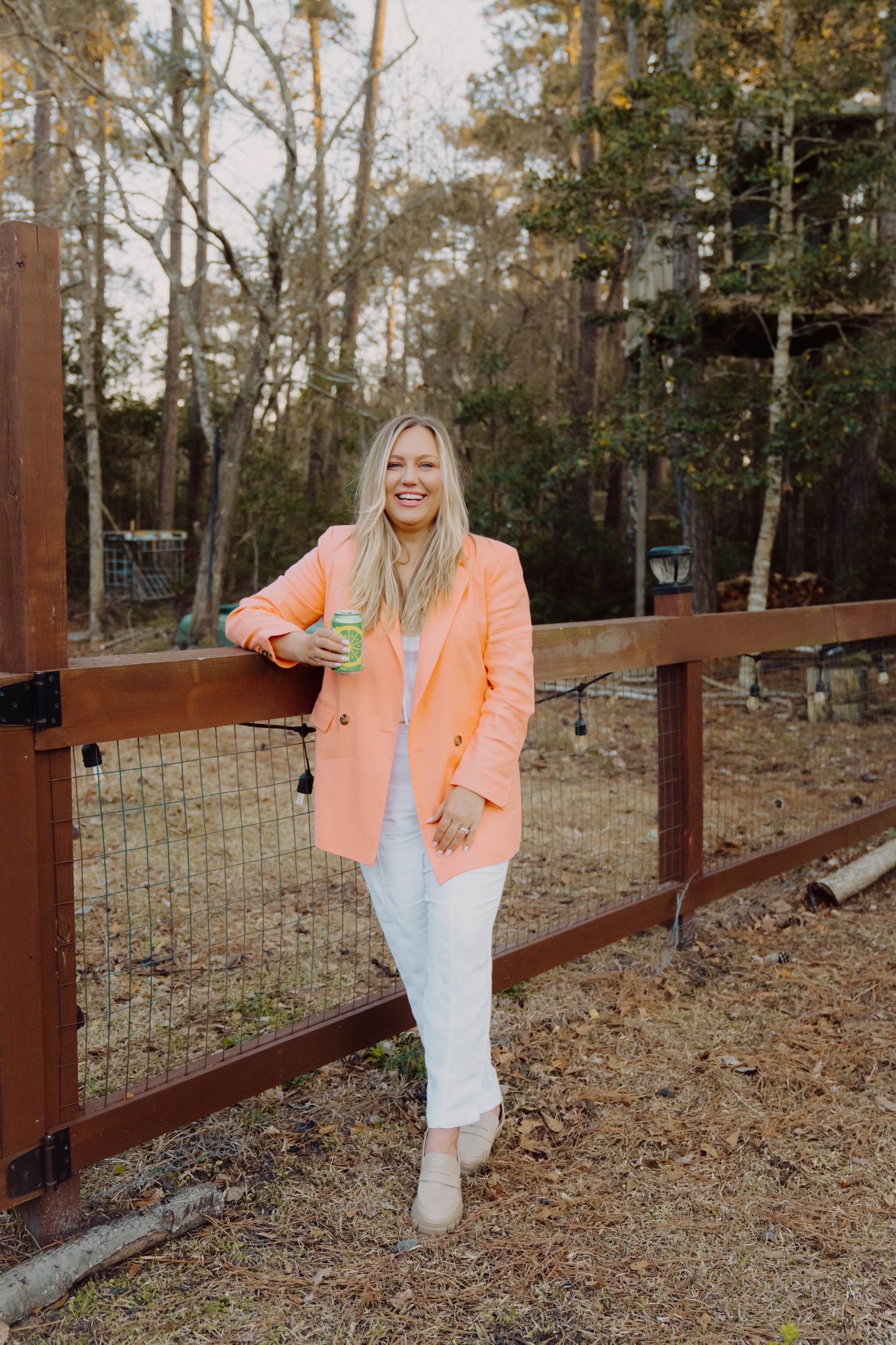Jen Benford standing beside a farm fence in a peach blazer